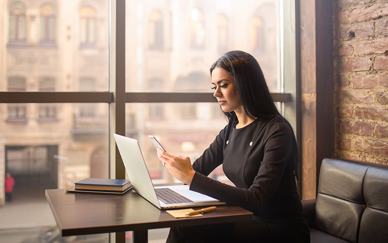 business woman with a laptop and looking at her phone